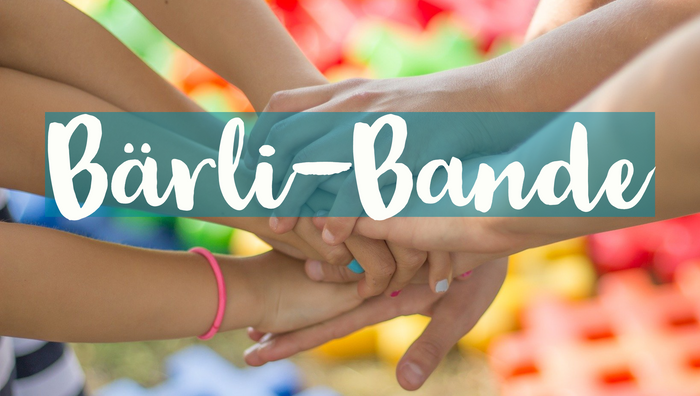 Ein Bild von vielen Weißen Händen, die übereinander gelegt sind. An einem Arm ist ein pinkes Haargummi zu sehen, einige Nägel sind bunt lackiert. Der Hintergrund ist ebenfalls bunt.